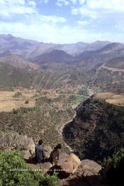 Image du Maroc Professionnelle de  Un berbère accompagné de sa chèvre assis sur des rochers qui surplombent un paysage d'une des vallées du Haut Atlas sur la route à travers  la montagne qui mène de Marrakech à Ouarzazate le Dimanche 24 Août 1997. (Photo / Abdeljalil Bounhar)
